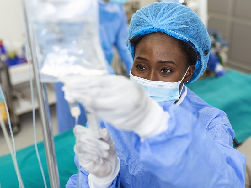 African american female Doctor in the operating room putting drugs through an IV - surgery concepts